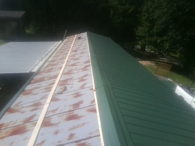 Old rusted panels beside newly installed green metal roofing — Wind Damage Roof Repair by Roofing Brothers in Preston