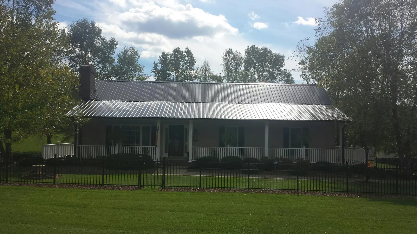 Gray metal roof on a brick ranch with a full width front porch — Gutter Guard Installation work by our crew in Preston